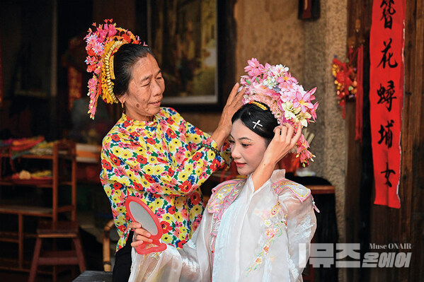 A tourist (right) is wearing flowery headwear at Xunpu Village of Quanzhou City, southeast China